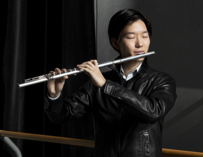 Yuan Yu jouant de la flûte traversière avec les yeux fermés.