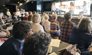Public assistant à une représentation de musique de chambre donnée par des violonistes et violoncellistes lors d'un concert sur une péniche à Paris.