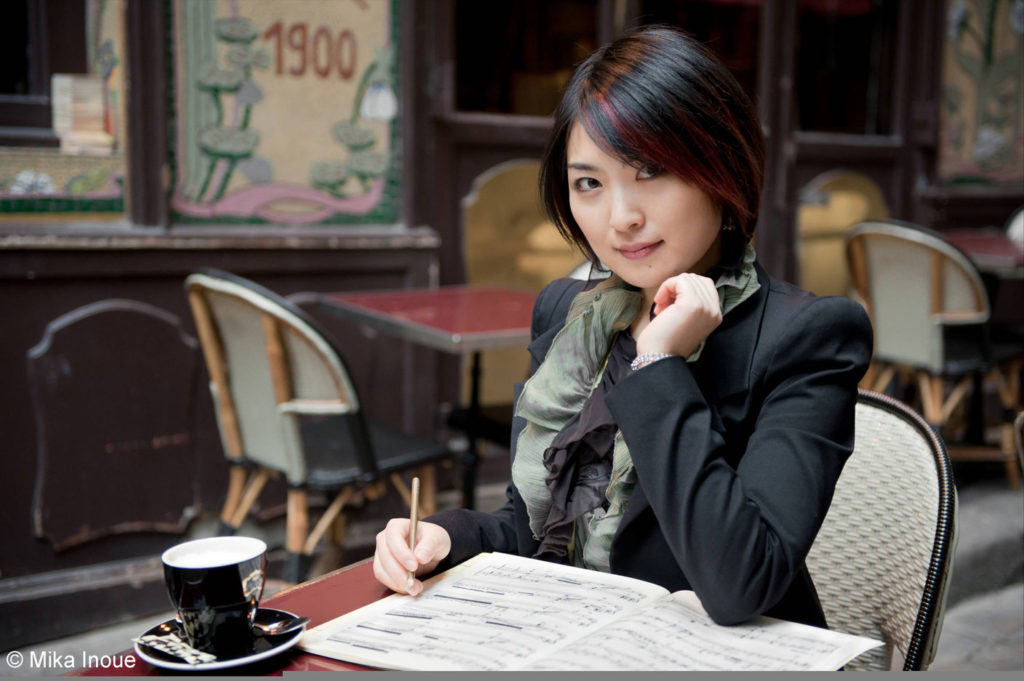 Kanae Endo assise à une terrasse de café à Paris annotant une partition de piano